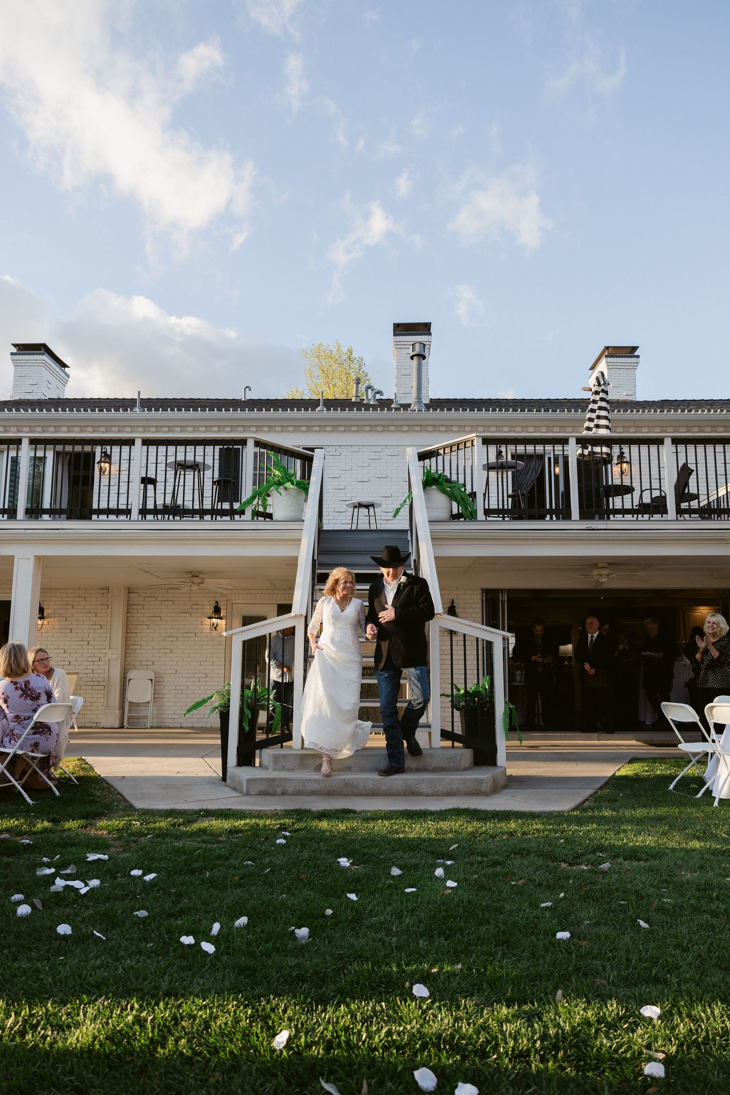 A modern mid-century home with white exterior features and large windows sits on a grassy lawn under a blue sky.