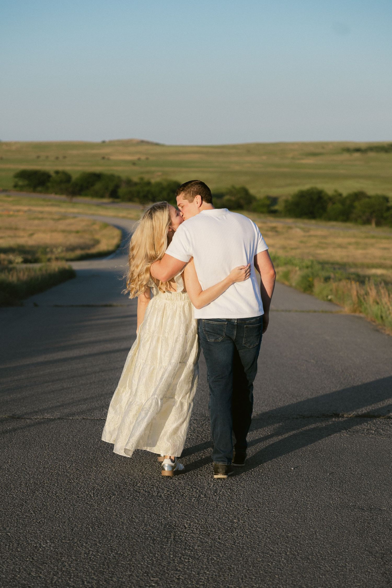 A sequence of affectionate moments between two people on a rural country road at sunset.