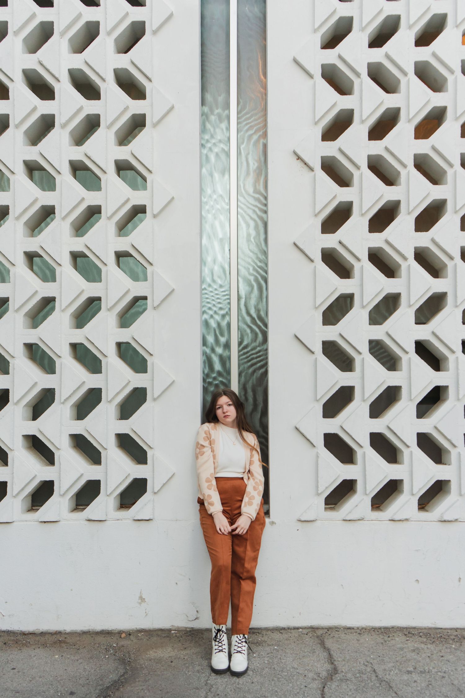 A series of four similar photos showing someone wearing brown overalls against a white geometric patterned wall.
