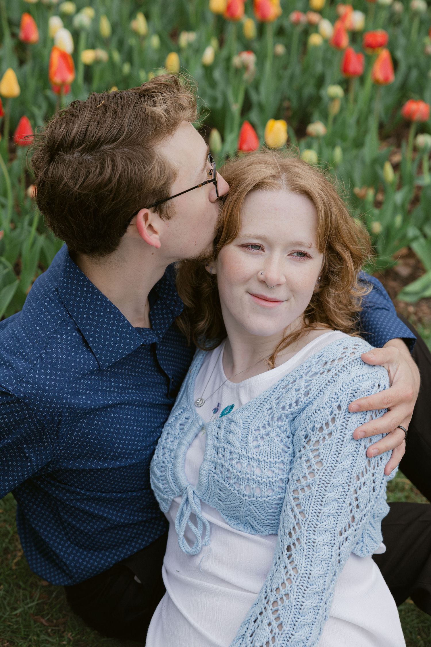 Intimate moment captured between couple in front of colorful spring tulip garden.