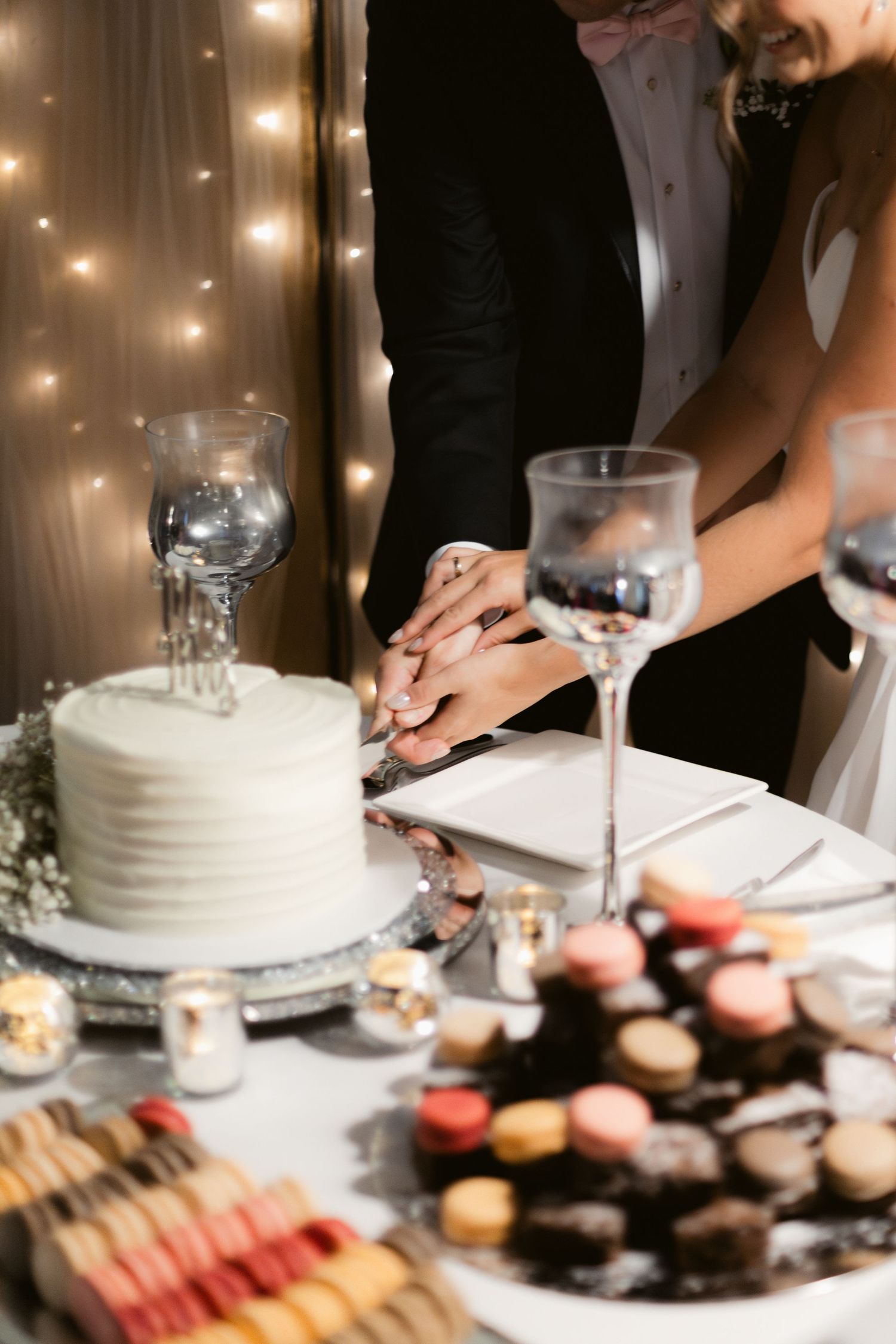 Wedding reception dessert table with white cake and assorted pastries being served in elegant setting.