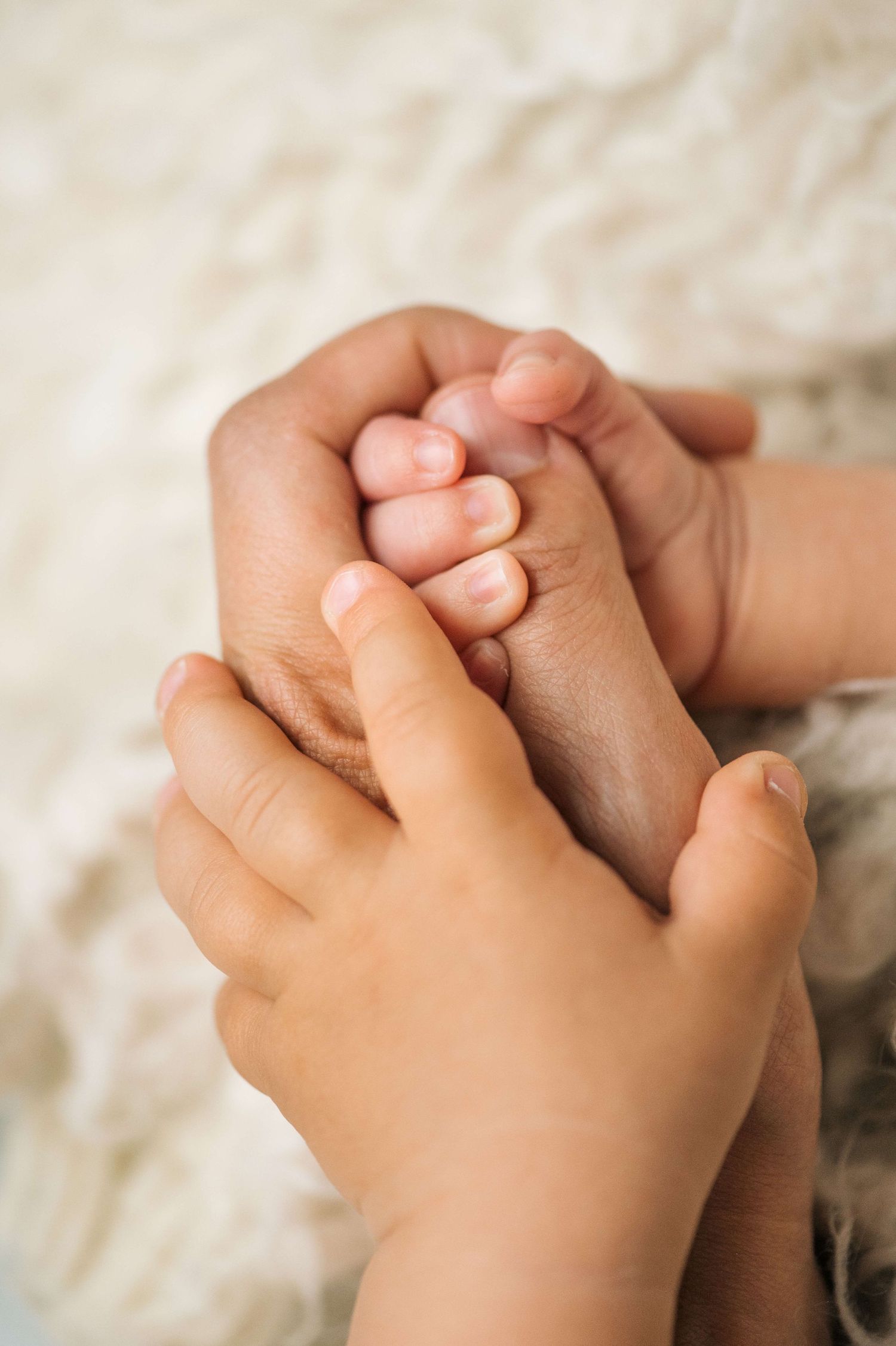 Close-up of a parent gently holding a newborn baby's tiny hand, symbolizing love and family bond.