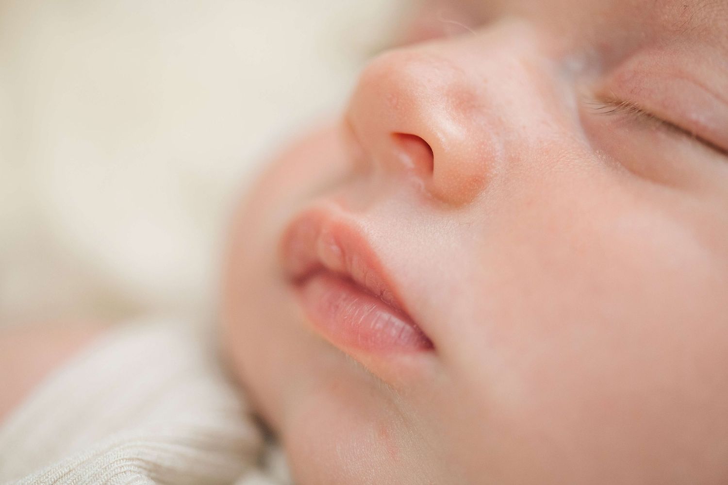 Close-up of a peaceful sleeping newborn baby's face with soft skin and delicate features.