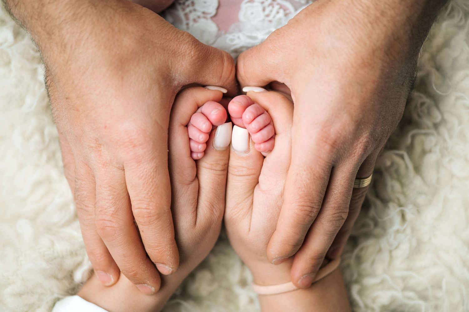 Parents gently cradling their newborn baby's tiny feet in their hands, symbolizing love and new parenthood.