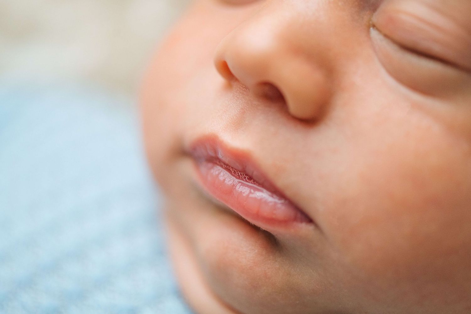 Close-up of a sleeping newborn baby's face with delicate lips and soft skin.