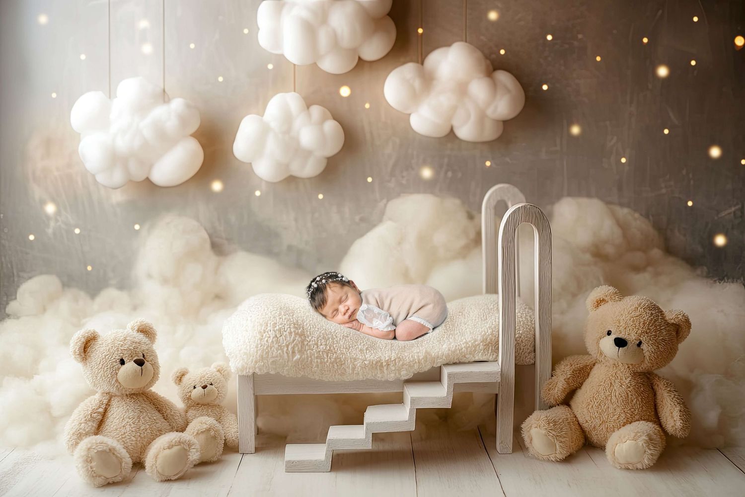 Newborn baby sleeping in a white miniature bed surrounded by fluffy clouds and teddy bears in a dreamy nursery setting.