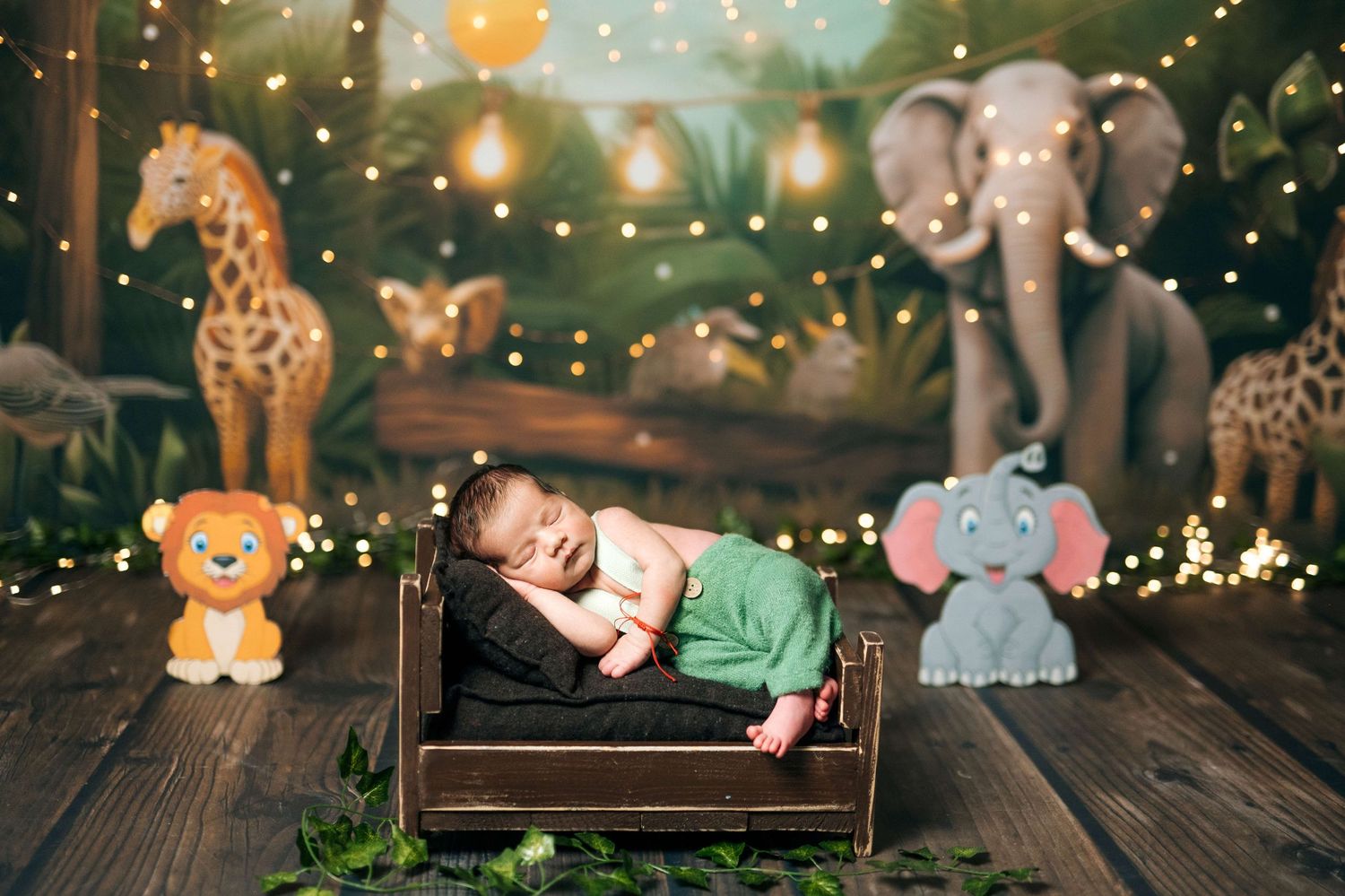 Newborn baby sleeping in a tiny wooden bed surrounded by jungle animal decorations and warm fairy lights.