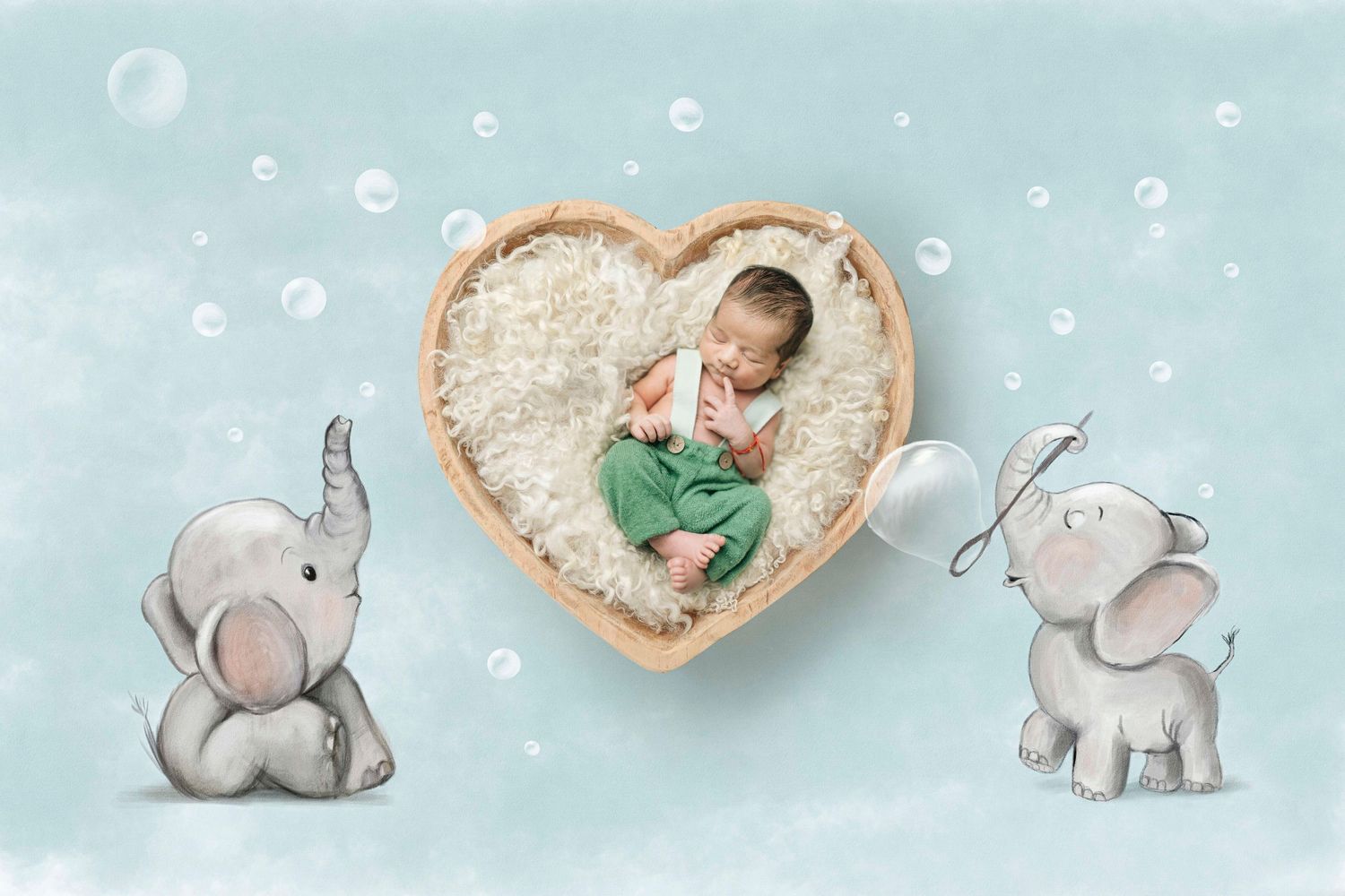 Newborn baby sleeping in heart-shaped wooden bowl surrounded by illustrated elephants blowing bubbles on soft blue background.