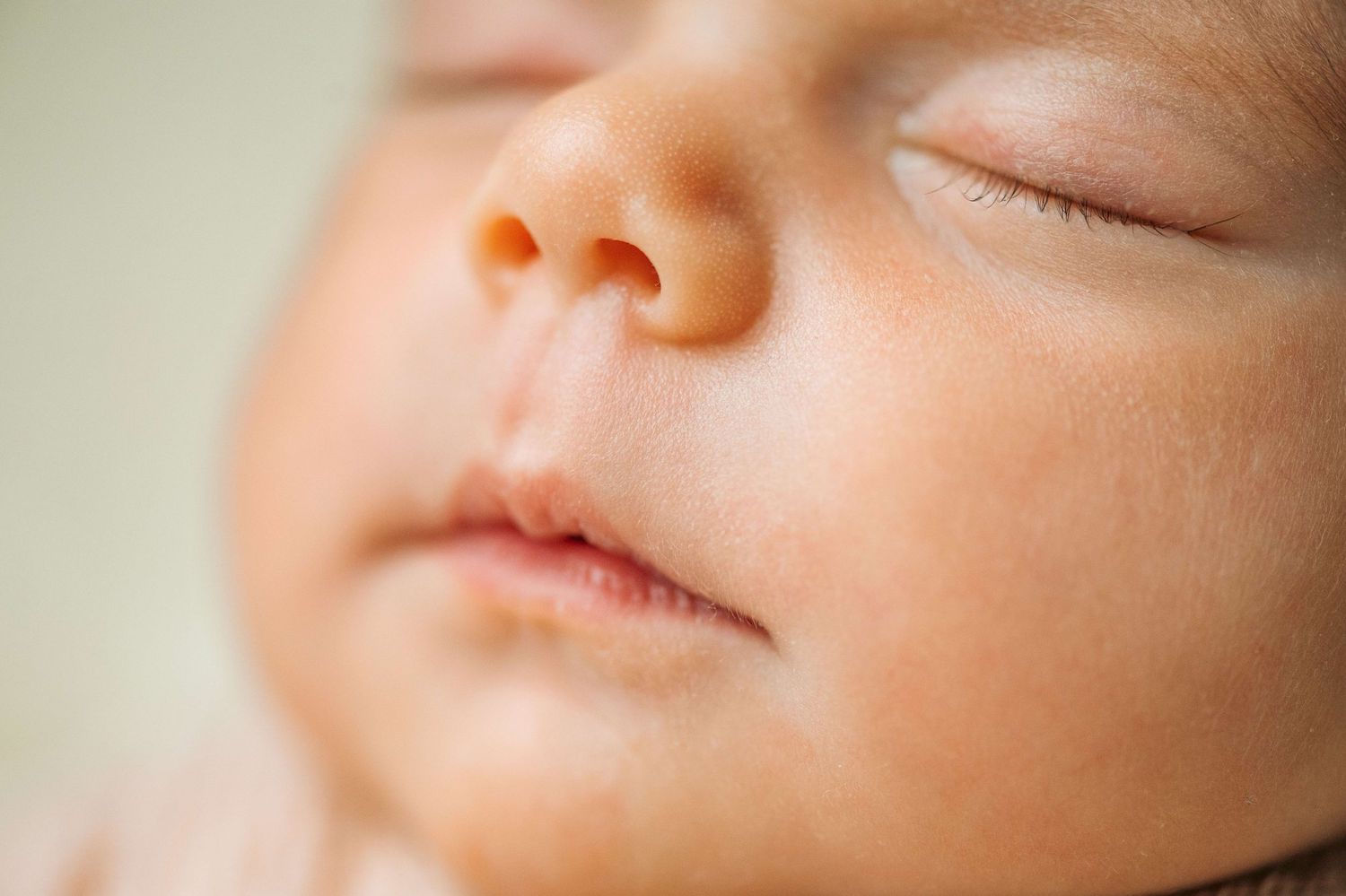 Close-up of a peaceful sleeping newborn baby with soft skin, tiny nose, and delicate features.