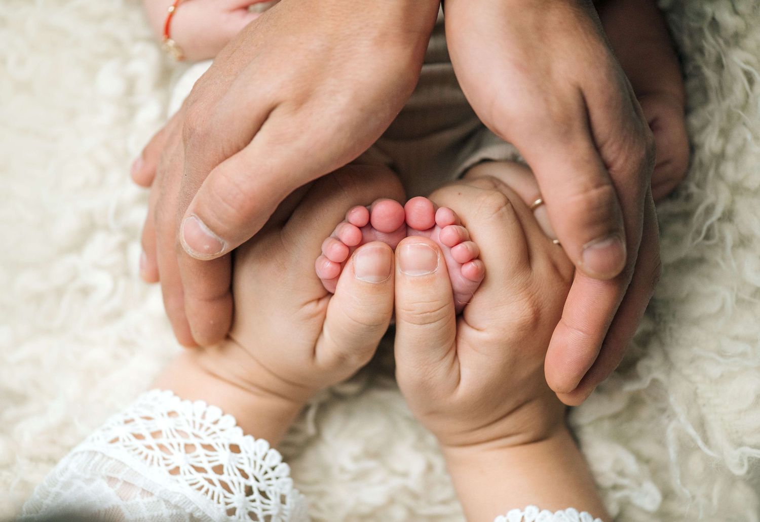 Parents cradling their newborn baby's tiny feet in their hands, a tender family bonding moment.