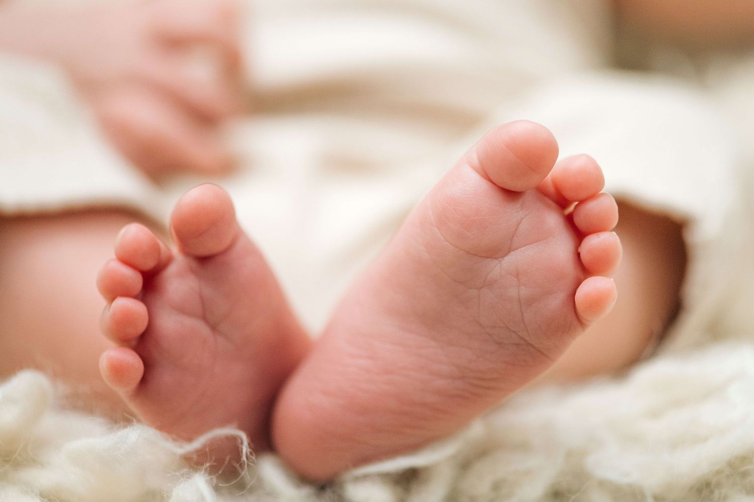 Close-up of adorable newborn baby feet resting on a soft white blanket.