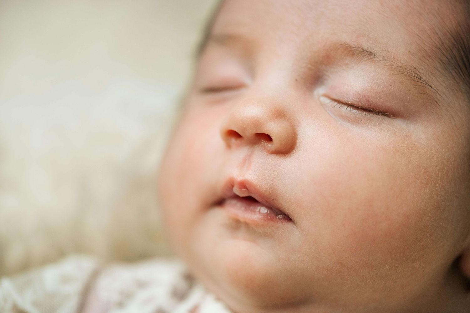 Close-up of a peaceful sleeping newborn baby with soft skin and delicate features resting on a cozy surface.