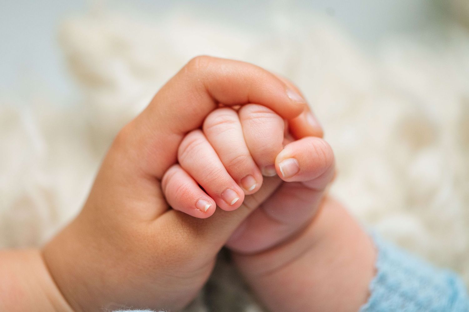 Close-up of a newborn baby gently gripping an adult finger, symbolizing love and new life.