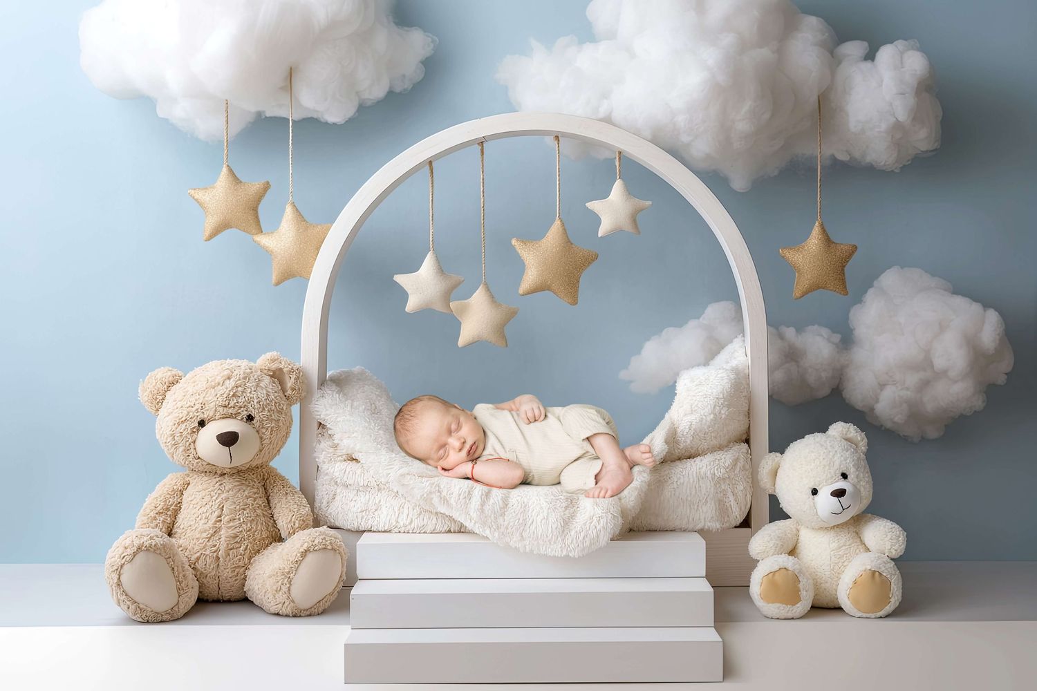 Sleeping newborn baby in white arch crib with teddy bears, star mobiles, and fluffy clouds on blue background.