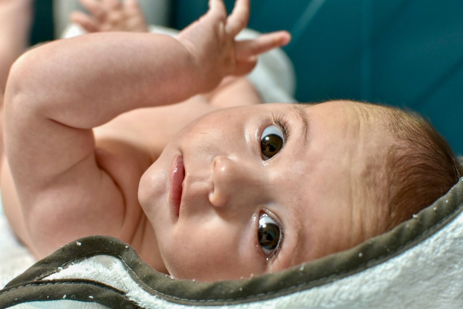 Bébé allongé sur le dos après le bain, avec un regard malicieux, à Langon