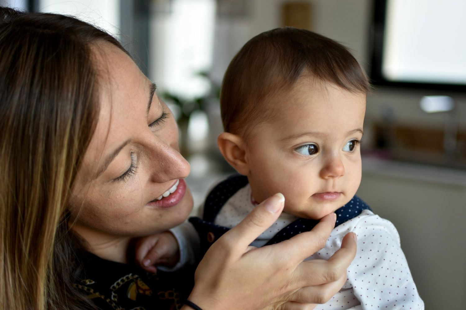 Mère caressant le visage de sa fille dans la cuisine de leur maison à Langon, en Sud-Gironde