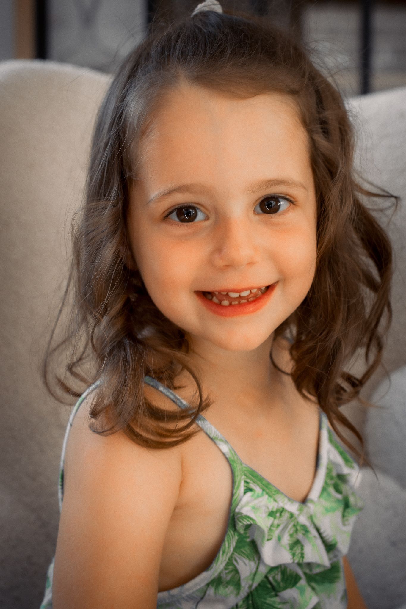 Portrait d'une fille de 3 ans, souriante, assise sur un fauteuil dans une maison située à Langon, Sud-Gironde