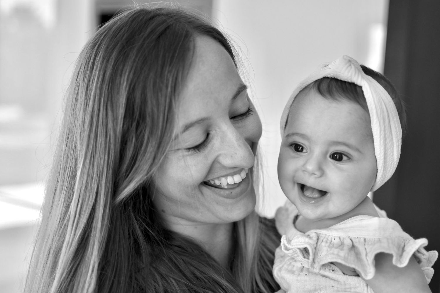 Portrait en noir et blanc d'une mère et sa fille souriantes dans leur salon à Langon