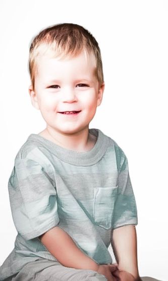 Smiling toddler boy with blonde hair wearing a light green striped t-shirt, posed against a white background.