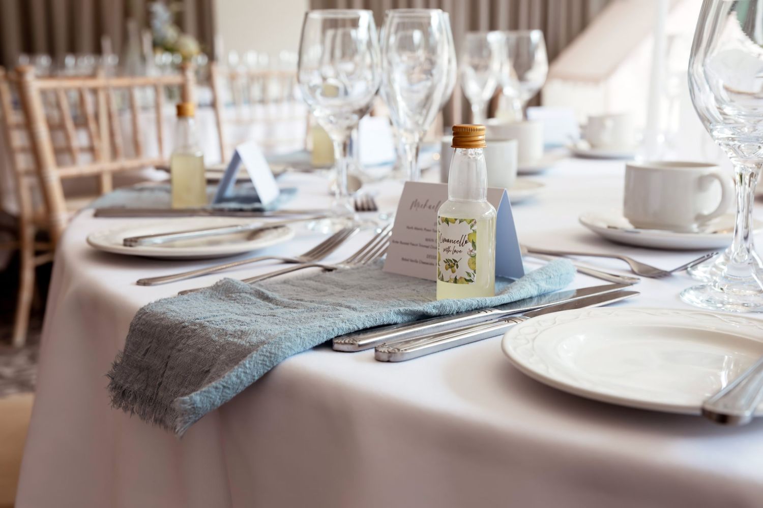 Elegant wedding reception table setting with blue napkins, crystal glassware, and fine china plates.