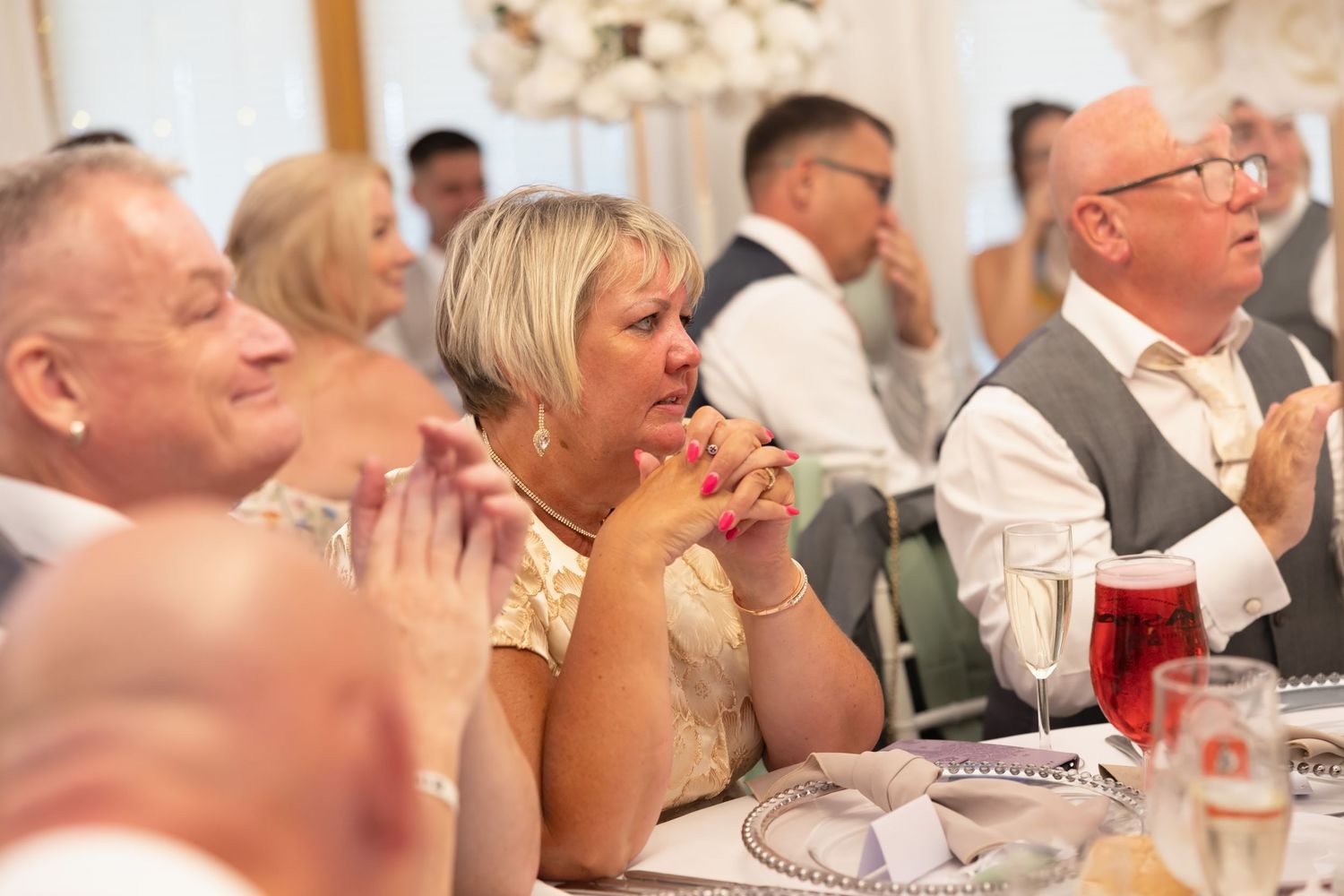 Wedding guests applauding and smiling during speeches at a elegant reception.
