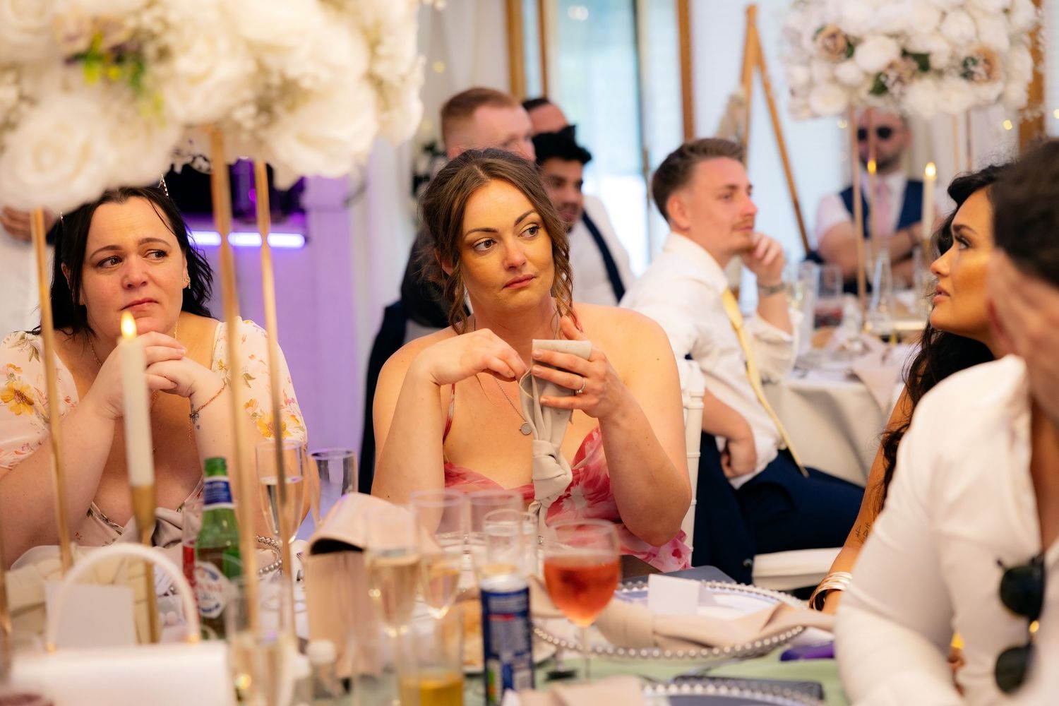 Wedding guests seated at elegantly decorated reception tables with floral centerpieces.