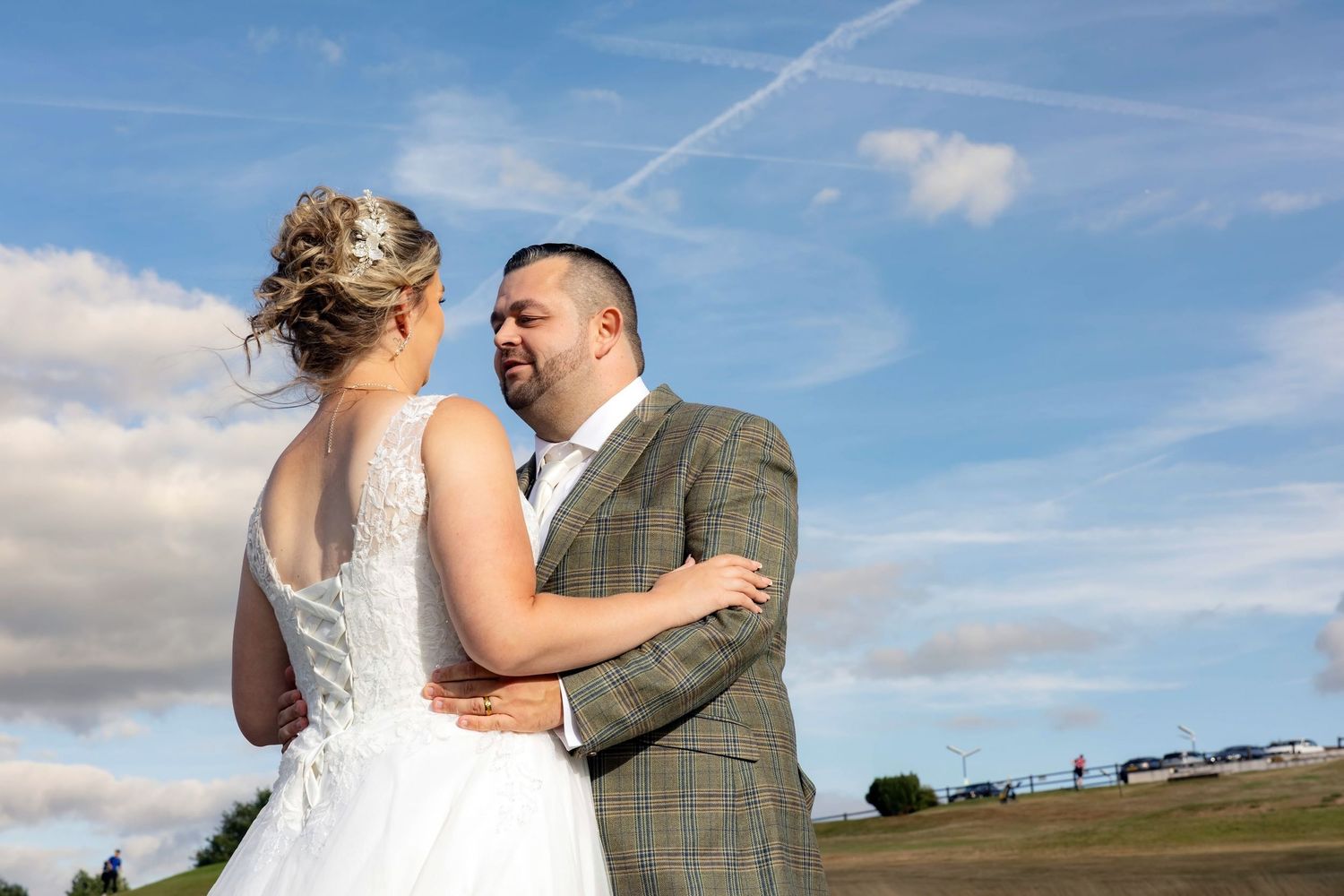Bride and groom embrace and smile at each other outdoors under a bright blue sky on their wedding day. south Wales weddings