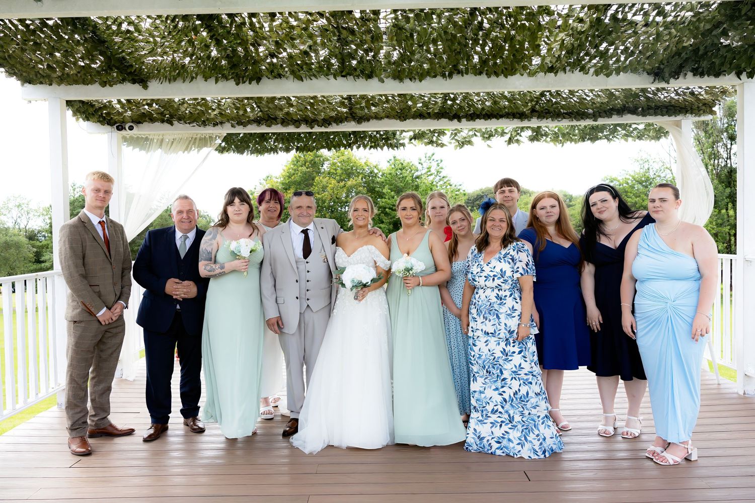 Wedding party group portrait on deck with bridesmaids in mint green dresses and guests.