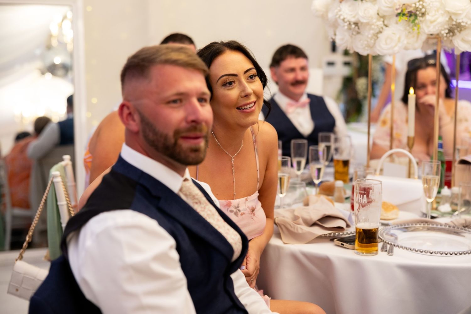 Couple smiling together at a beautifully decorated wedding reception table.