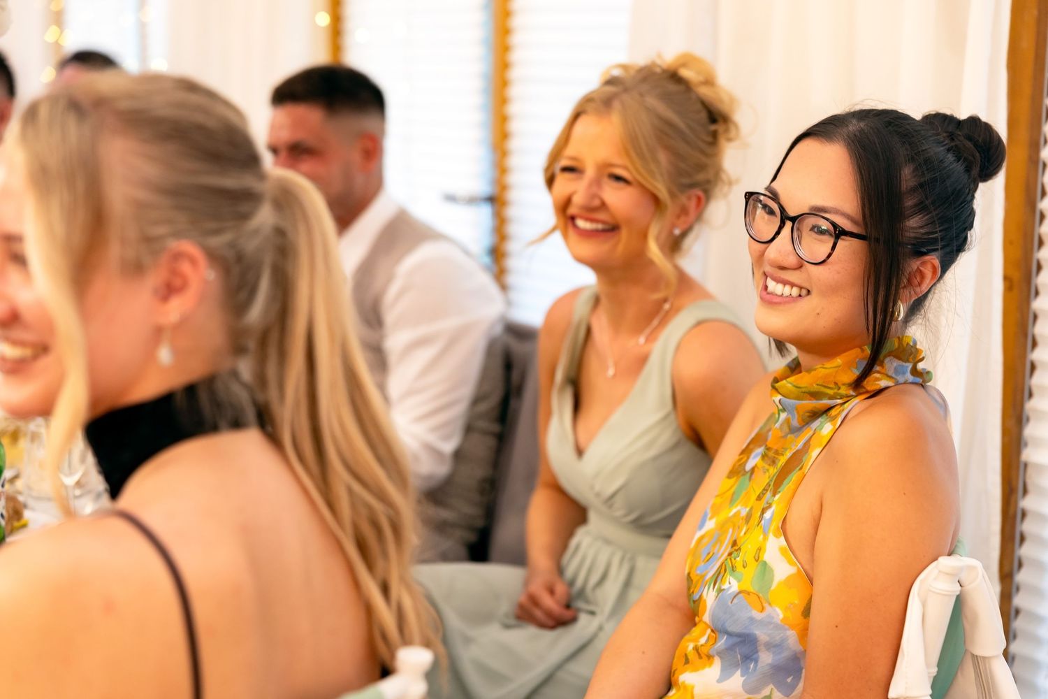 Smiling wedding guests in bridesmaid dresses enjoying the reception celebration.