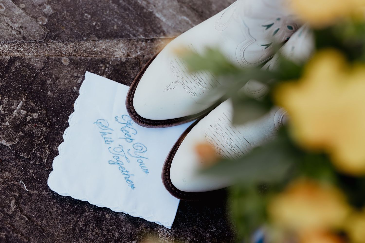 White cowboy boots beside a handwritten wedding vow note on stone steps with autumn foliage.