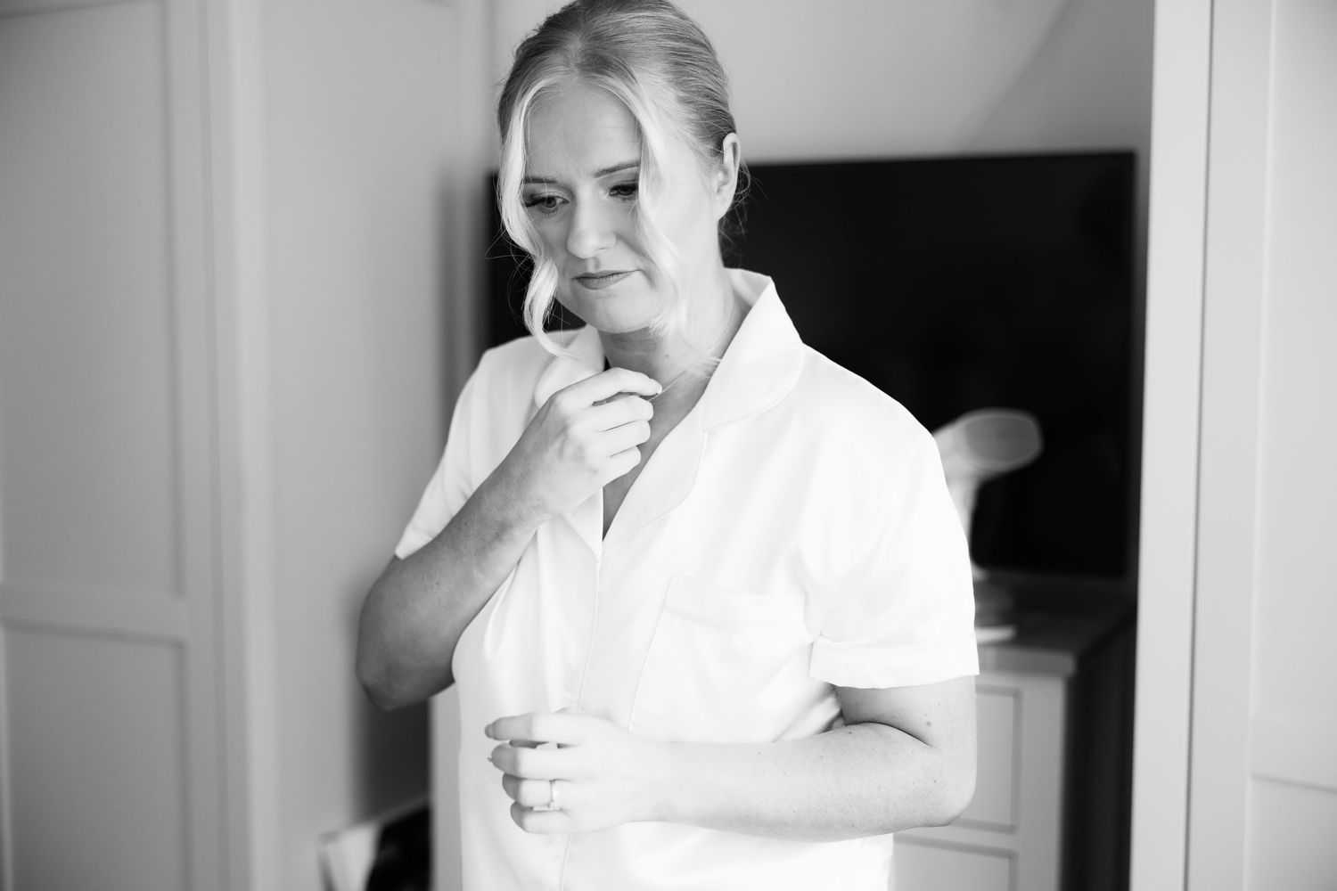 Elegant black and white portrait of bride in white robe during wedding preparations.