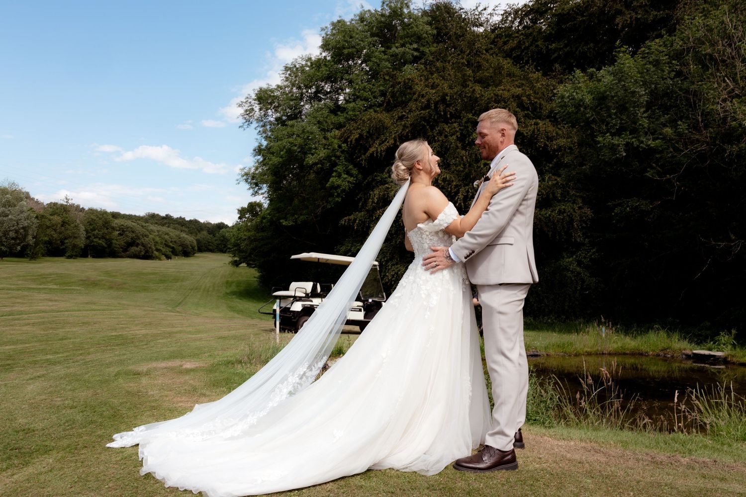 A bride and groom share a romantic moment on a lush green golf course on their wedding day. Wedding photography south Wales.
