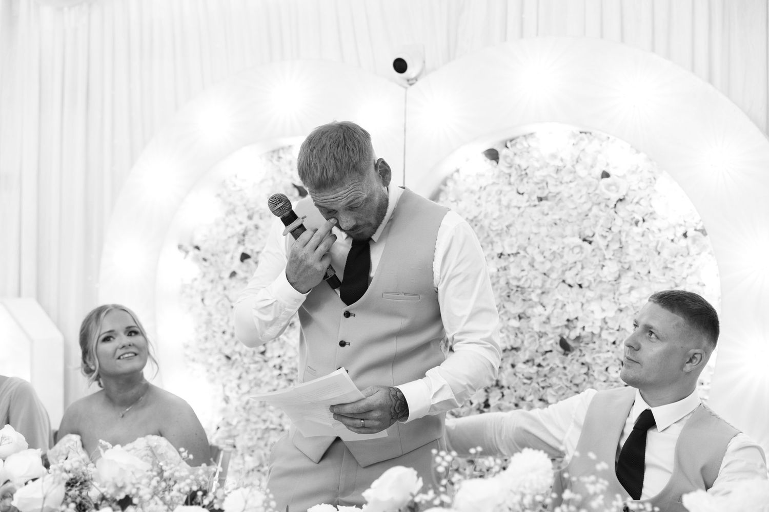 Emotional groomsman reads his wedding speech at an elegant black and white wedding reception.