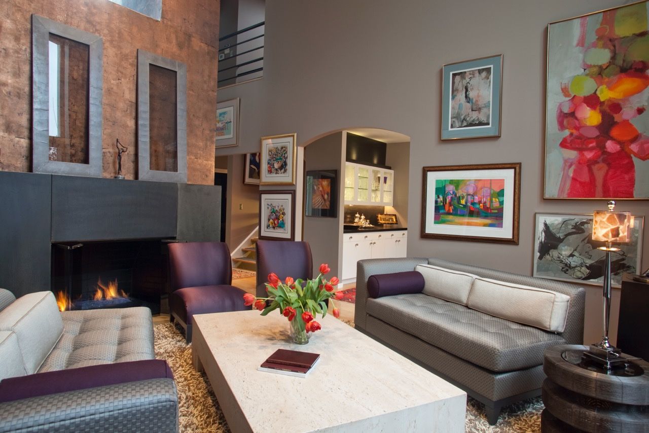 Contemporary loft living room with linear fireplace, art-covered walls, leather sofas, and exposed brick. Interior designer in The Sea Ranch
