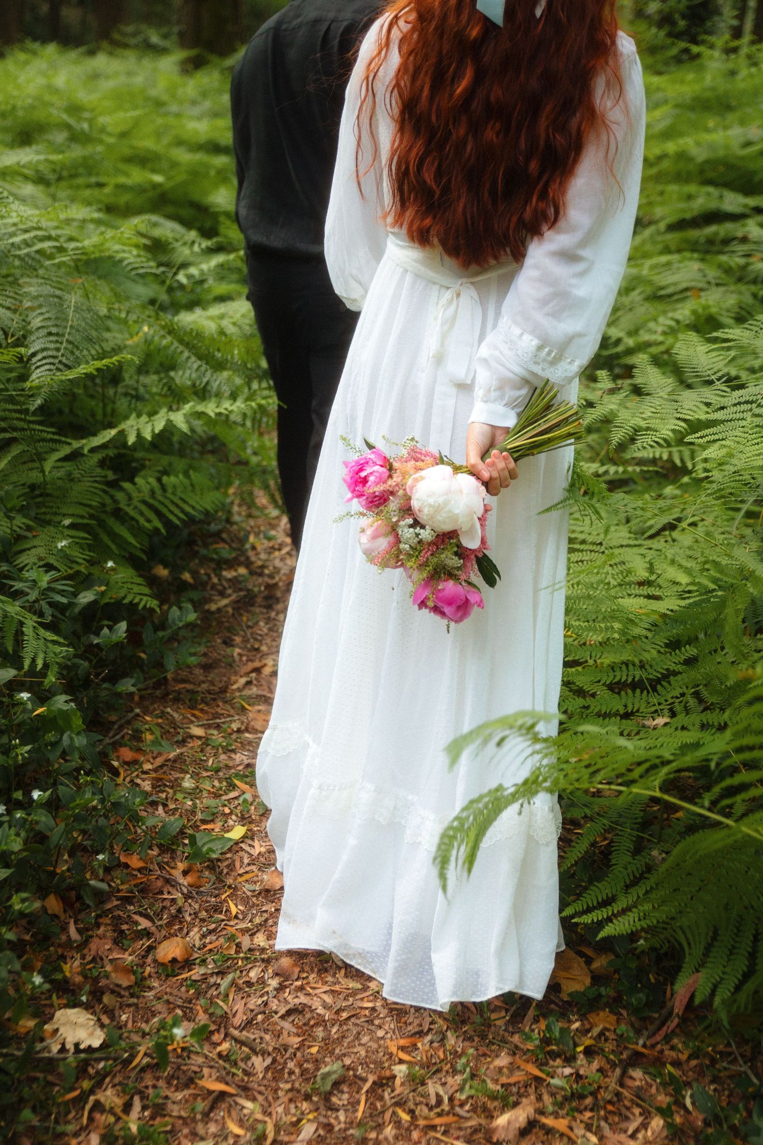 Detalhe de noiva de vestido branco a segurar um bouquet entre fetos na floresta, numa sessão de noivado romântica em Ovar.