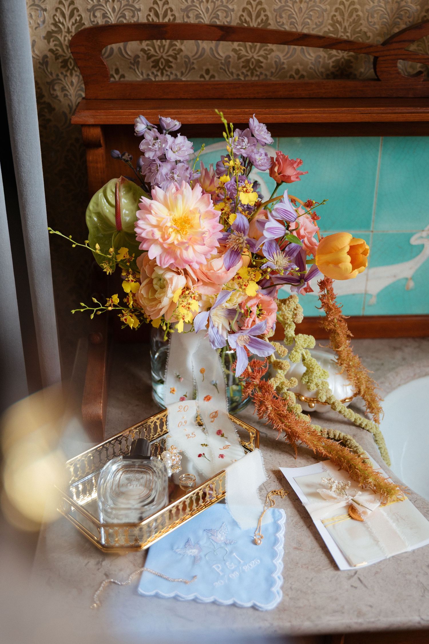 Bouquet de flores coloridas e detalhes do casamento dispostos sob uma mesa, durante a preparação da noiva, no Porto, numa vibe romântica.
