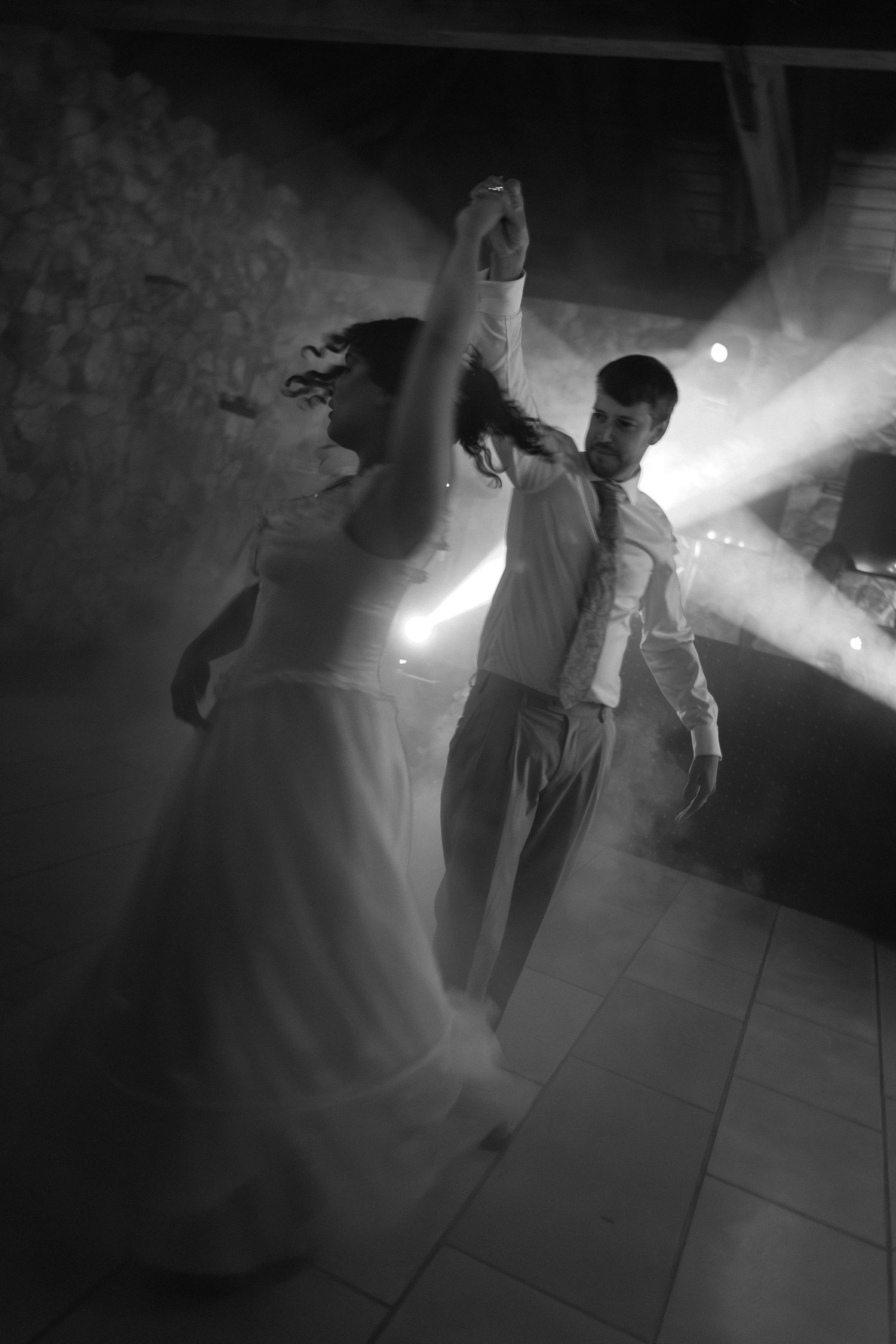 Fotografia a preto e branco de noivos a dançar durante festa, movimento com imagem desfocada.
