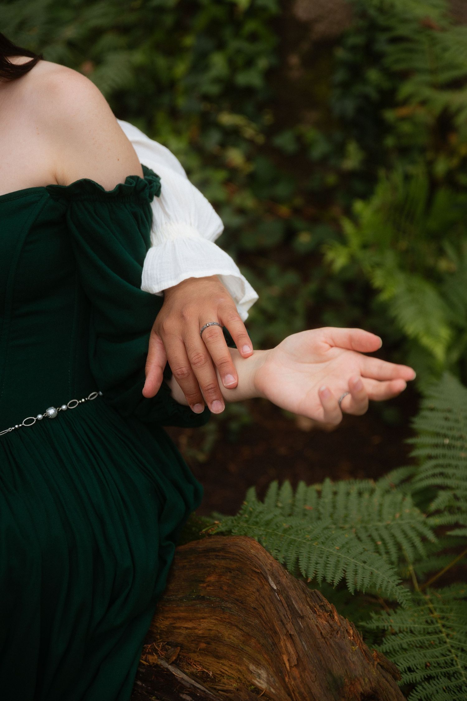 Mãos de um casal entrelaçam-se numa floresta, destacando o carinho e as alianças durante uma sessão romântica no dia do casamento em Sintra.