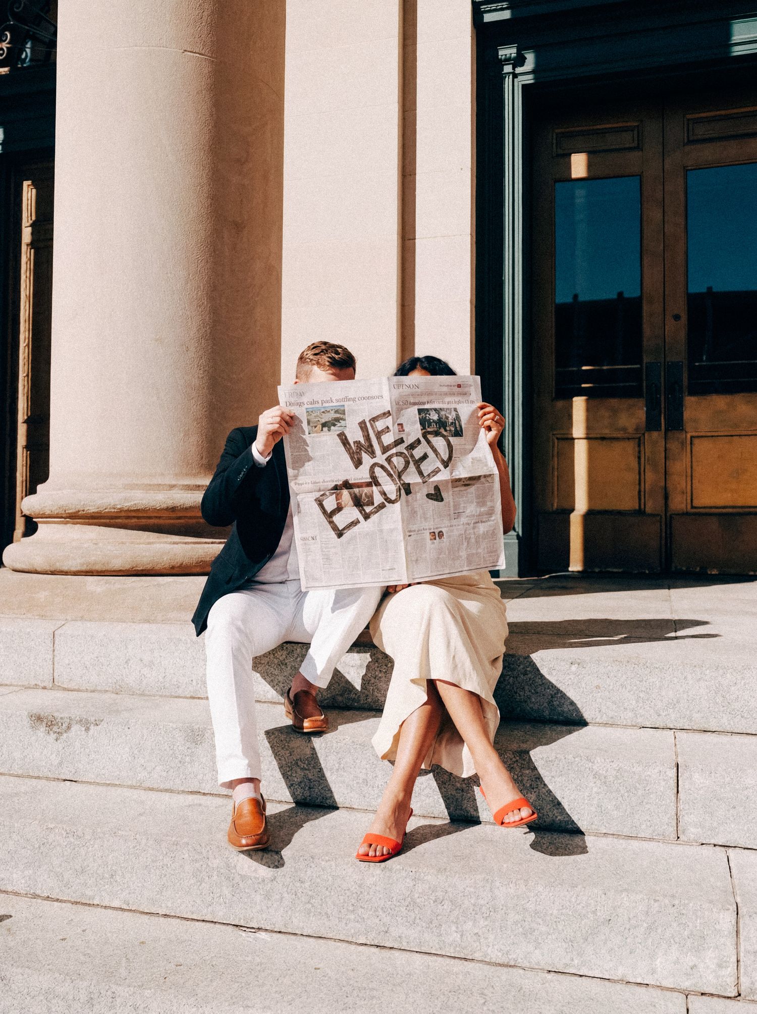 Newlyweds holding a Just Eloped sign on the courthouse steps.