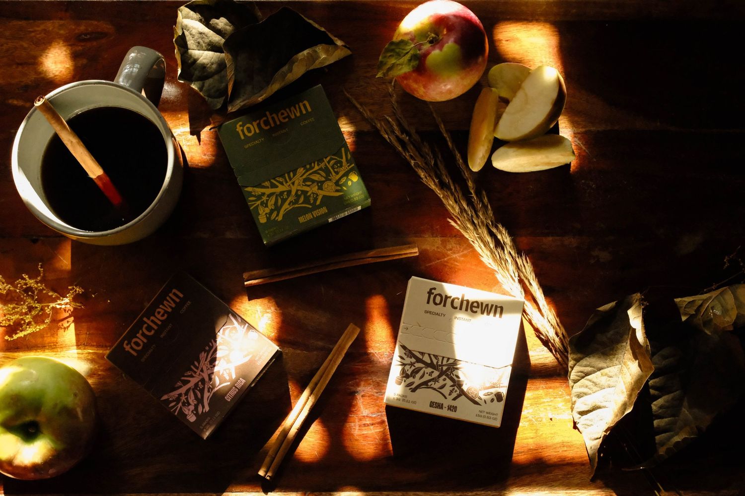 Overhead coffee product arrangement with packaging, apples, and a dark cup.