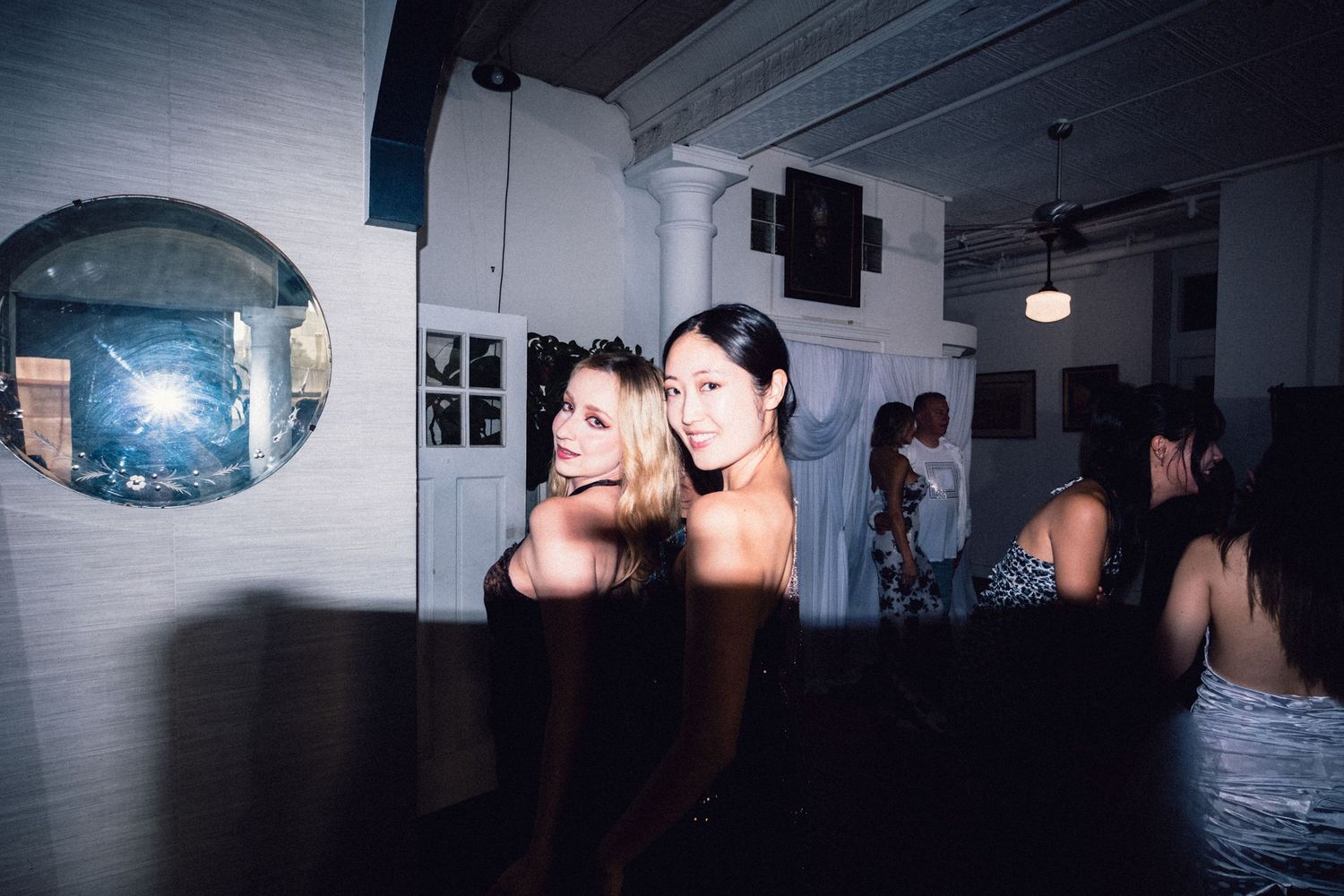 Two women posing together at an intimate Soho fashion event.
