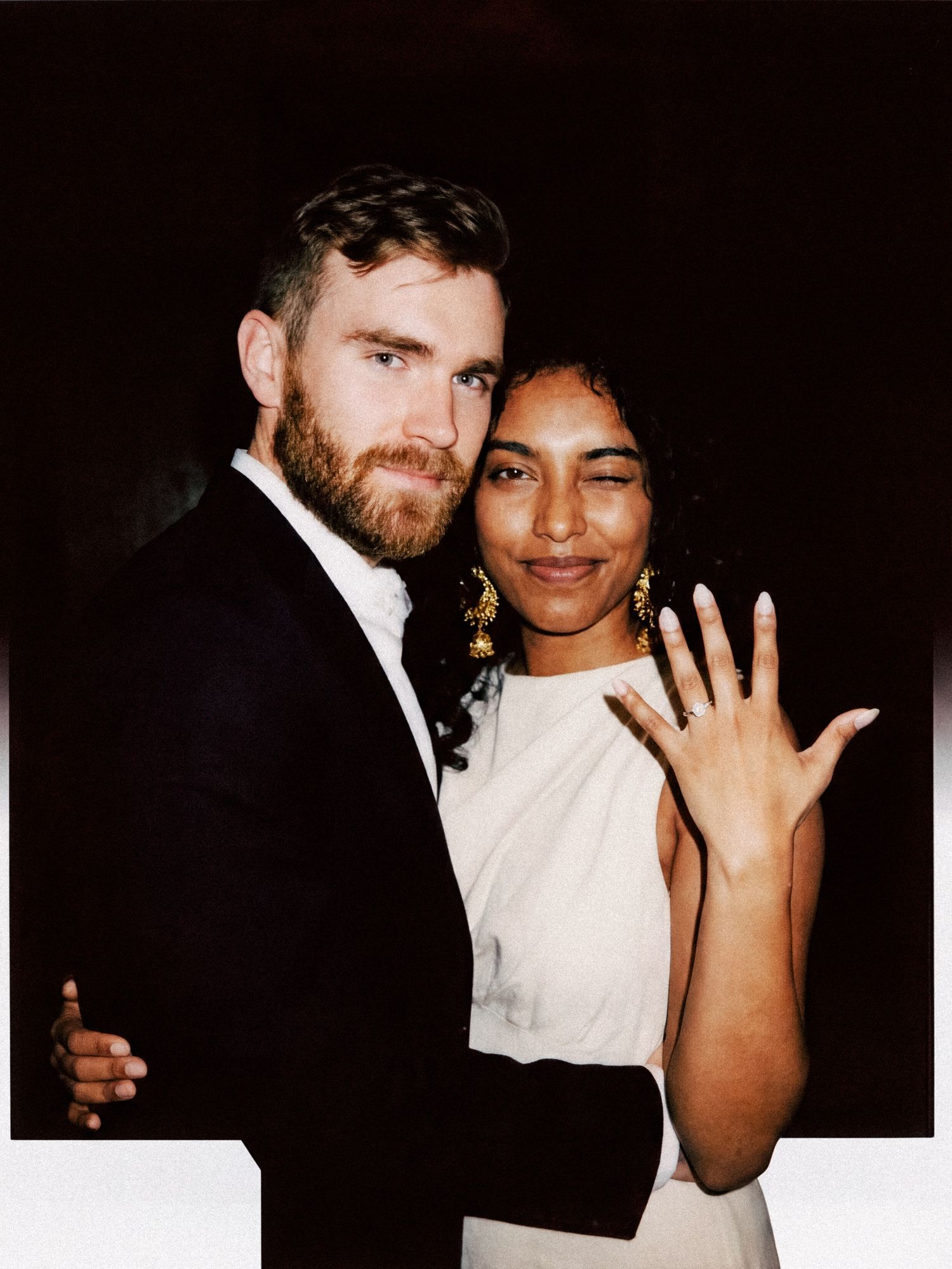 Newlywed couple smiling as the bride displays her wedding ring.