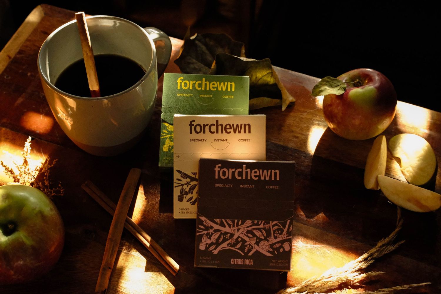 Specialty coffee packages styled with a ceramic cup, apples, and warm light.