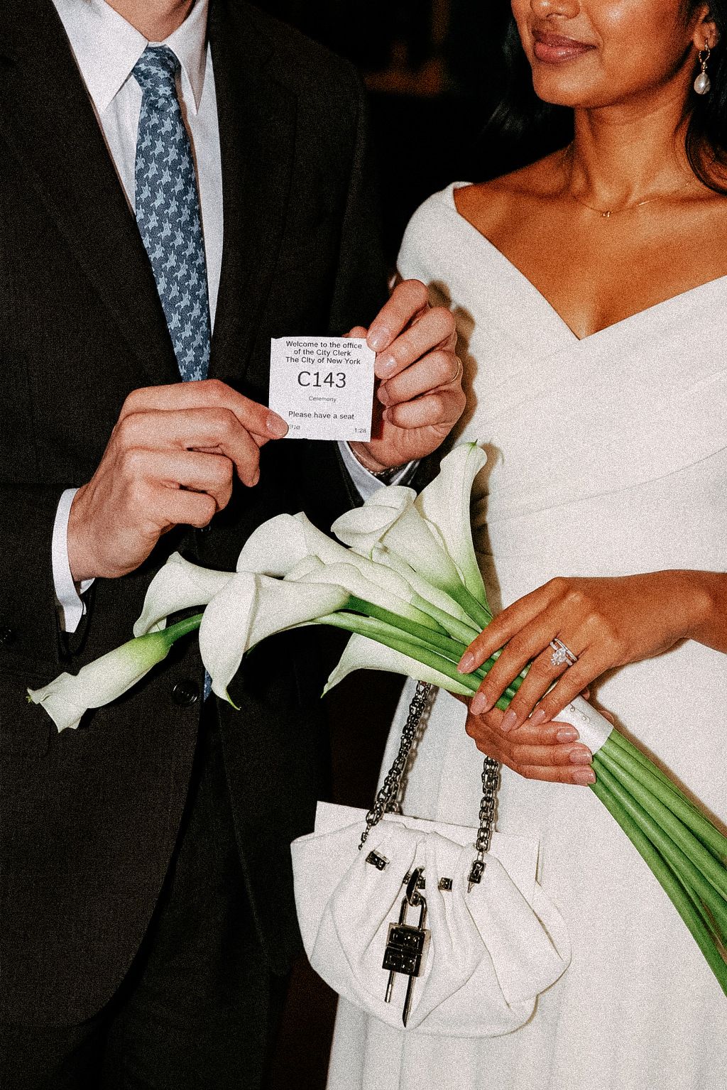 Bride and groom holding their marriage certificate, bouquet, and wedding ring.
