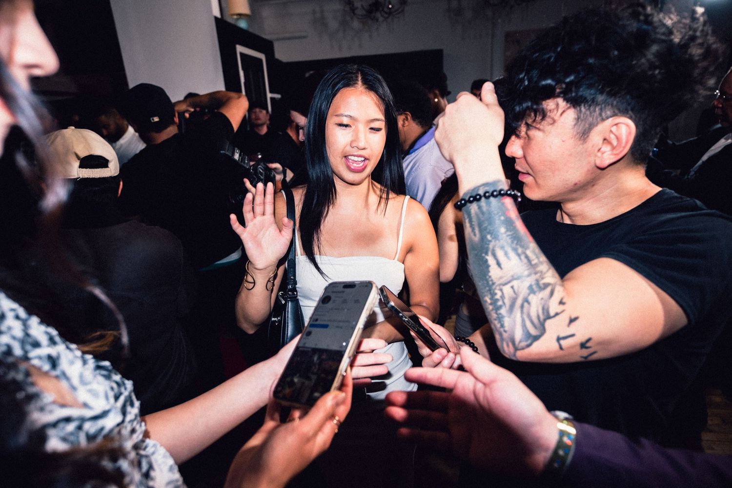 Fashion-event guest surrounded by cameras and guests recording the moment.