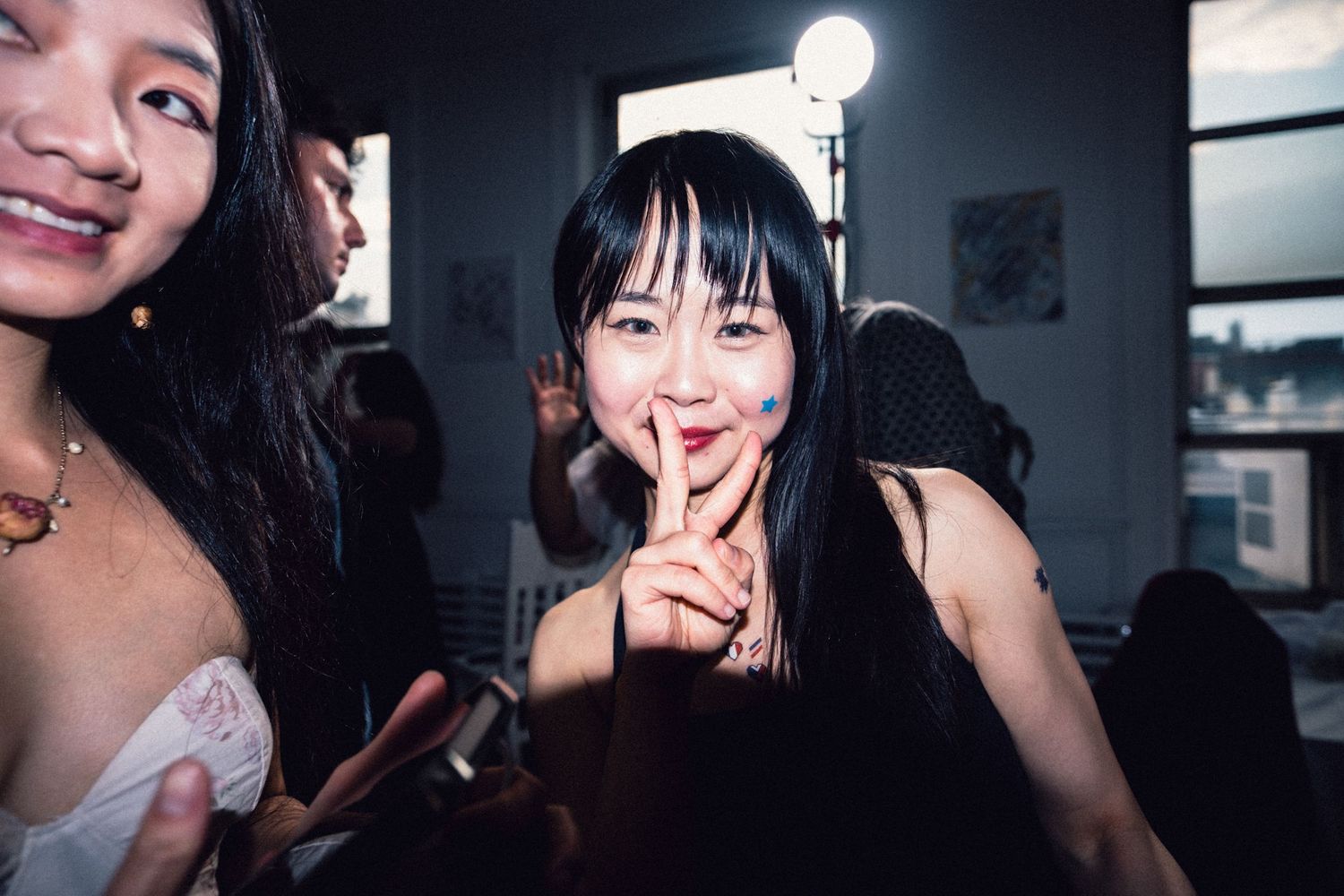 Fashion-event guest making a playful gesture toward the camera.