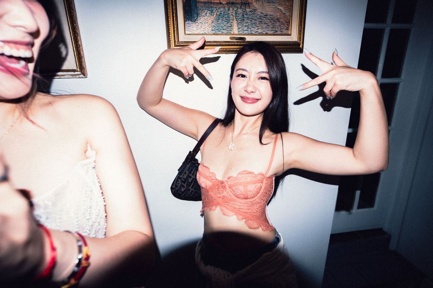 Guest in an orange fashion look posing playfully at a Soho event.