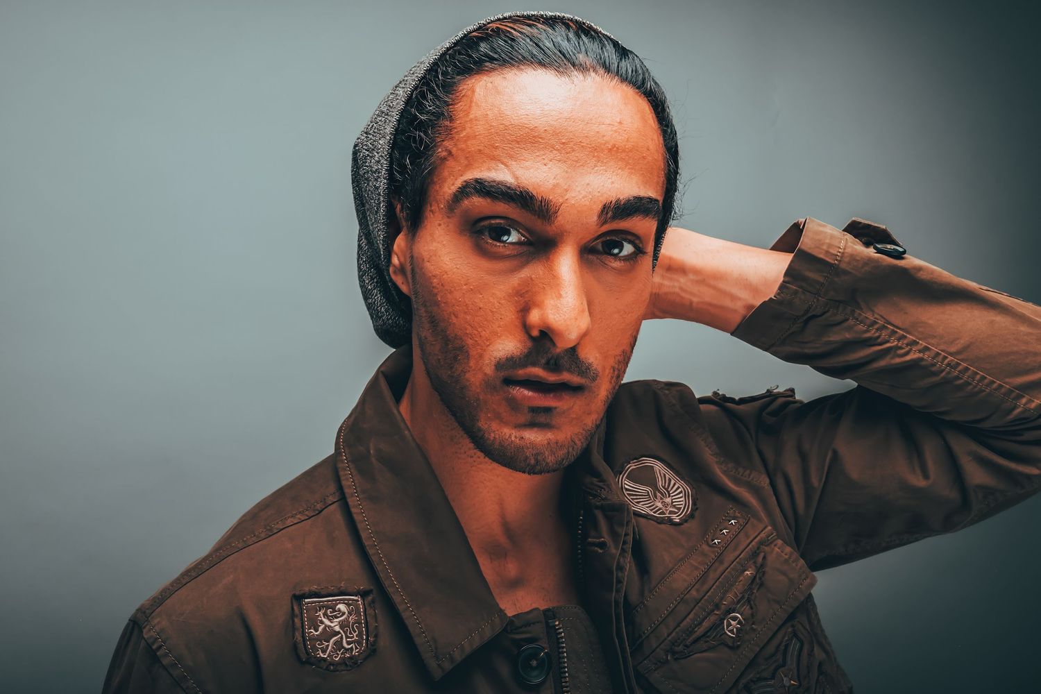 Cinematic studio portrait of a man in a brown jacket against a muted background.