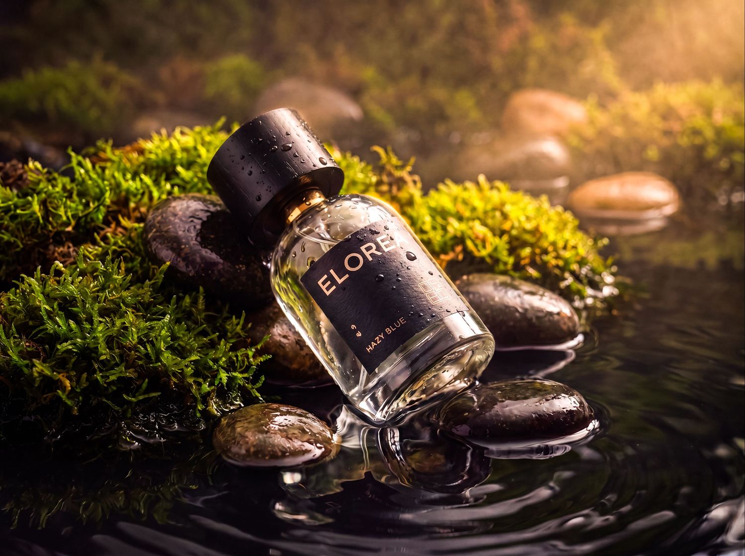 Luxury fragrance bottle resting beside moss and reflective water.
